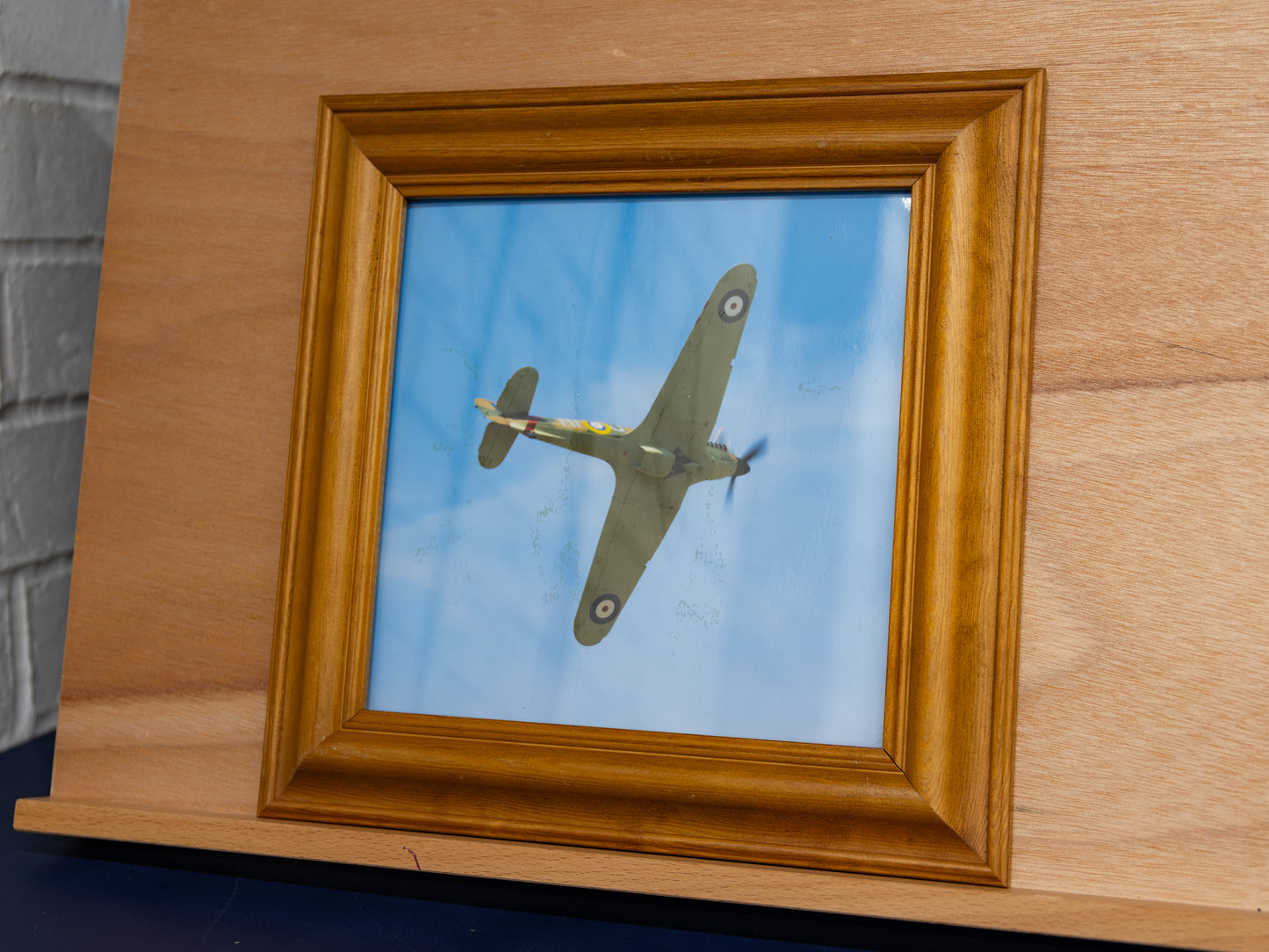 Framed BBMF Hawker Hurricane photo on easel, angled view showing aircraft underside.