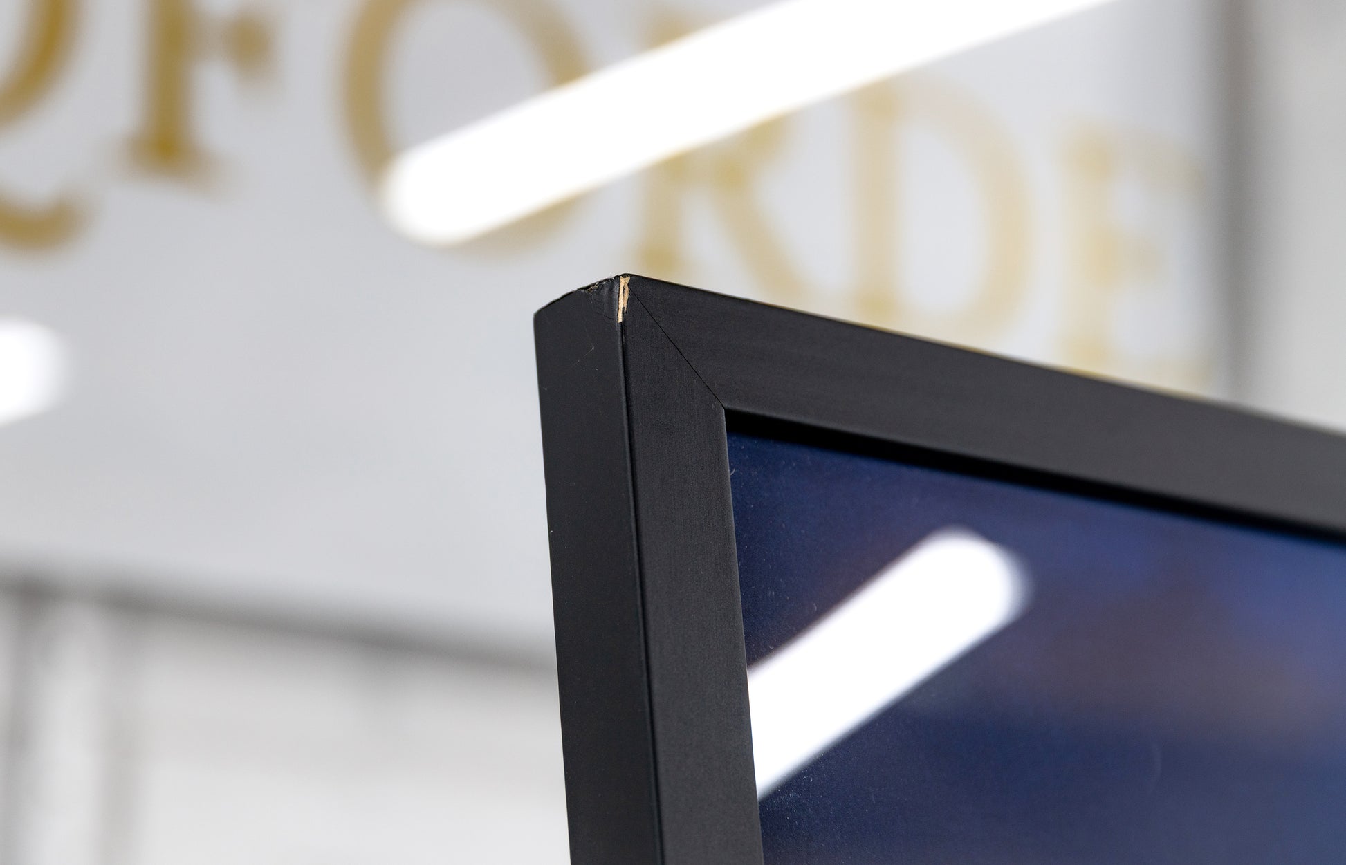 Top frame corner with visible cosmetic chip in the black coating