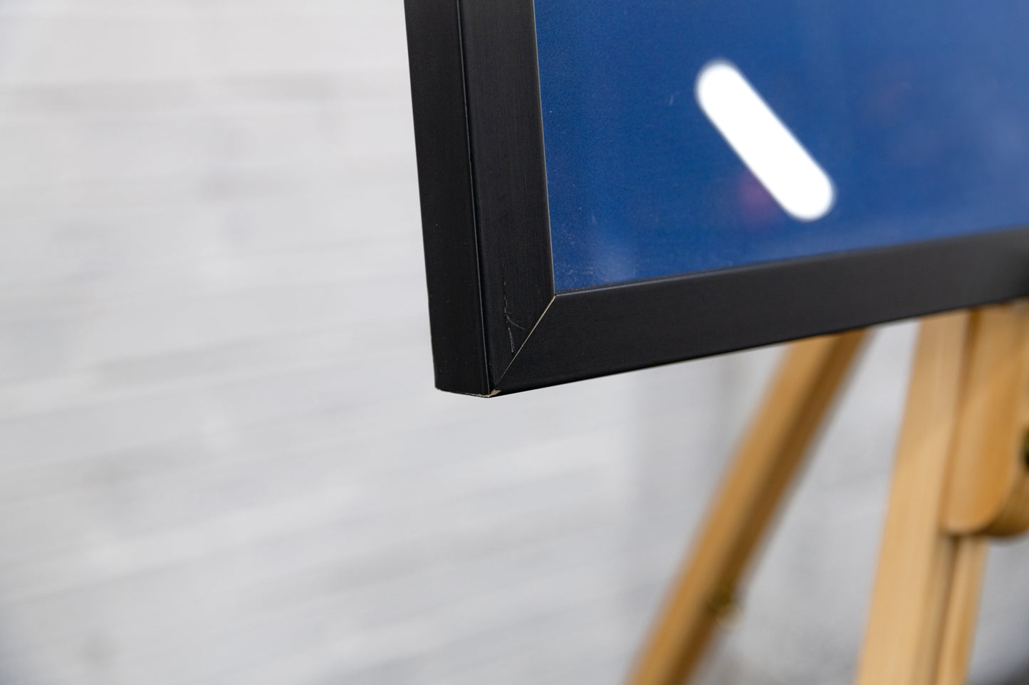 Bottom corner join showing minor scuffing and a tiny nick to the black frame