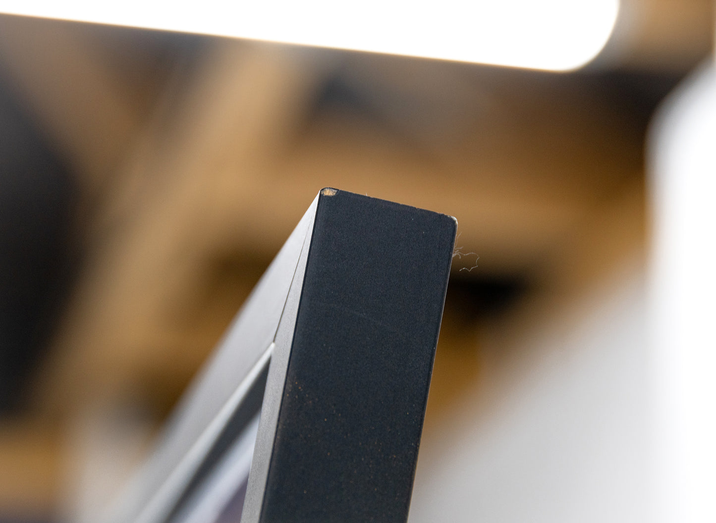 Close-up of a top frame corner with a small chip on the matte-black finish