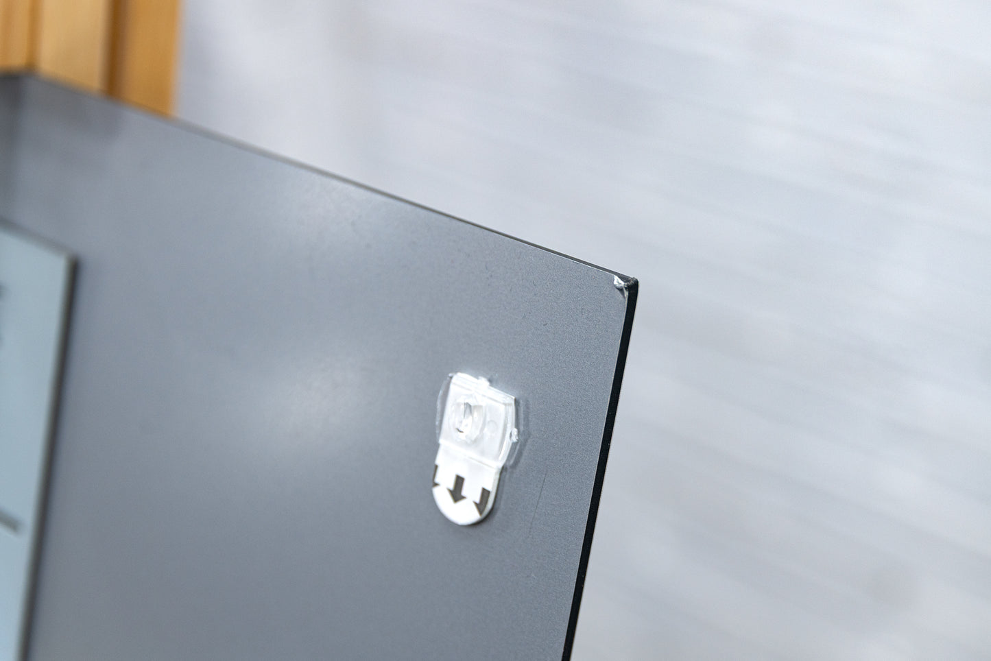 Close-up of the aluminium panel’s rear top-right corner showing a small cosmetic nick next to a clear hanging tab