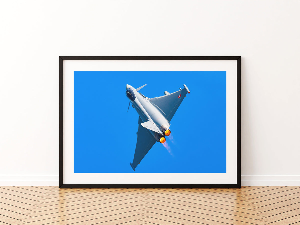 Austrian Air Force Eurofighter Typhoon climbing with afterburners lit against a deep blue sky, aviation photo wall art print in a black frame