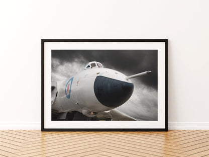 Nose of an anti-flash white Avro Vulcan bomber under a dark stormy sky, aviation photo wall art print in a black frame