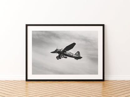 Westland Lysander banking under a streaked sky, black and white, aviation photo wall art print in a black frame