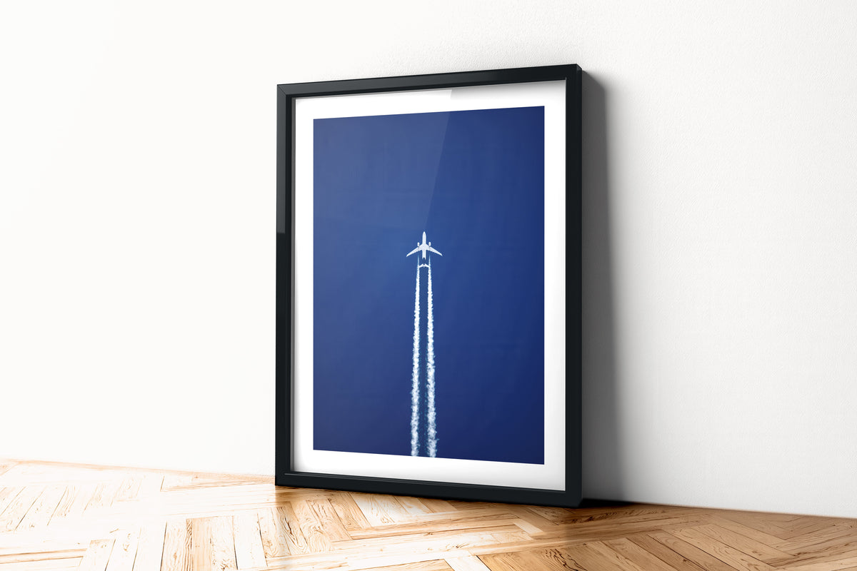 Airbus A330 at cruising altitude trailing twin contrails across a deep blue sky, aviation photo wall art print in a black frame