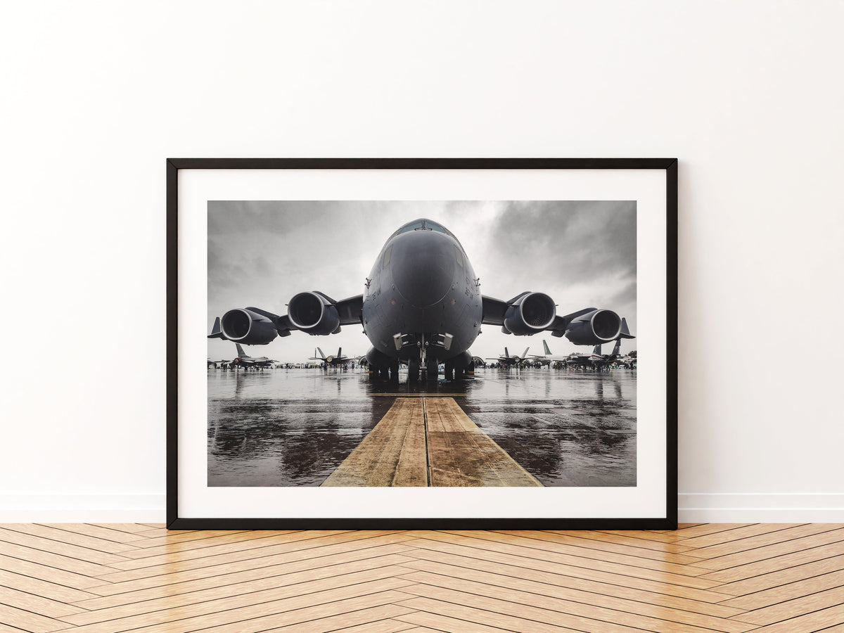 United States Air Force C-17 Globemaster III head-on on a rain-soaked static line under grey cloud, aviation photo wall art print in a black frame