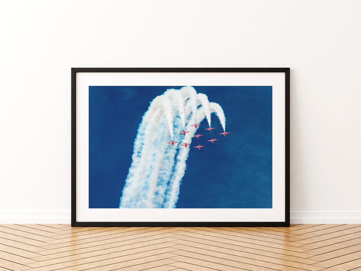 Nine Red Arrows Hawks climbing together with white smoke against a deep blue sky, aviation photo wall art print in a black frame