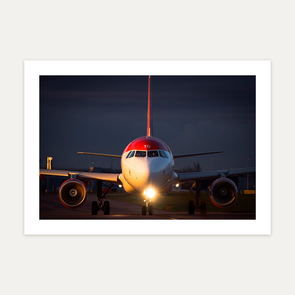 Red-tailed Airbus A321neo taxiing head-on at dusk with landing lights blazing, unframed A4 aviation photo print