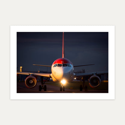 Red-tailed Airbus A321neo taxiing head-on at dusk with landing lights blazing, unframed A4 aviation photo print