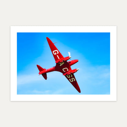 Red de Havilland DH88 Comet racer G-ACSS banking against a deep blue sky, unframed A4 aviation photo print